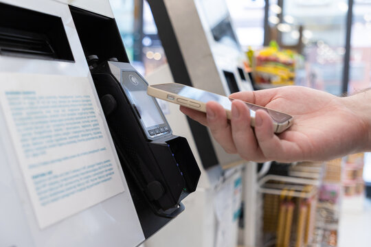 Person using a smartphone for fast contactless payment at a retail store self-checkout terminal, symbolizing modern digital transaction processes