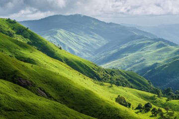 Fototapeta premium Lush Green Mountain Slopes under Cloudy Sky, Scenic Rolling Hills Landscape