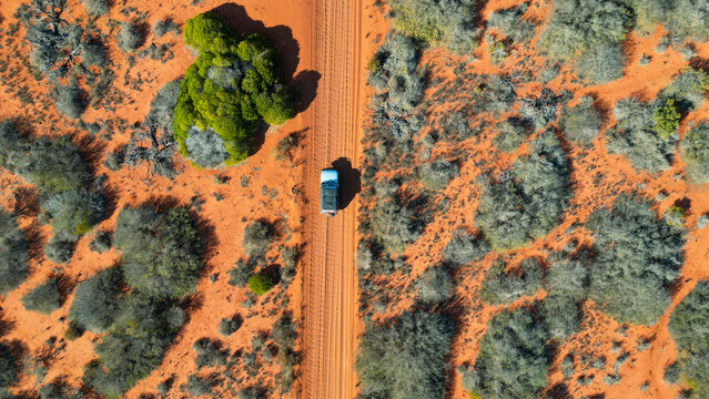 A car driving through the red soil of Australia, seen from above