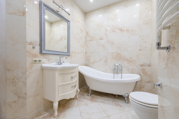 This bathroom showcases a luxurious freestanding tub, vintage-style cabinetry, and polished tiles, creating a serene and sophisticated atmosphere for relaxation.