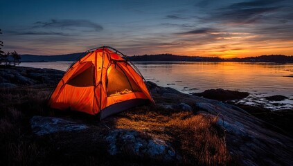 Orange tent illuminated at sunset on rocky shoreline