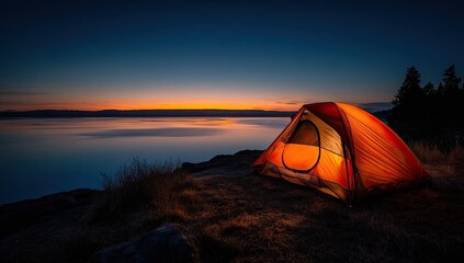 Illuminated orange tent on a cliff overlooking a tranquil lake at sunset