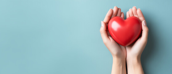 Fototapeta premium A pair of hands carefully holding a red heart shape against a clean, light blue background, perfect for illustrating concepts of giving, charity, or love