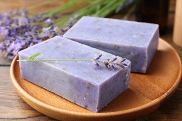 Soap bars and lavender flowers on wooden table, closeup