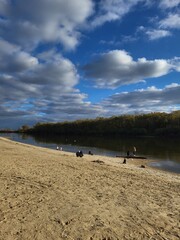 Sandy riverbank with cloudy sky in autumn