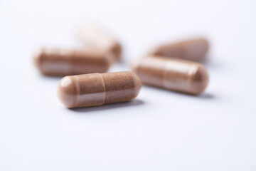 Ashwagandha (Withania somnifera) capsules. Concept for a healthy dietary supplementation. Bright paper background. Close up. Copy space.