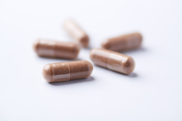 Ashwagandha (Withania somnifera) capsules. Concept for a healthy dietary supplementation. Bright paper background. Close up. Copy space.