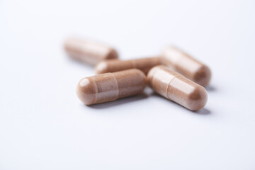 Ashwagandha (Withania somnifera) capsules. Concept for a healthy dietary supplementation. Bright paper background. Close up. Copy space.