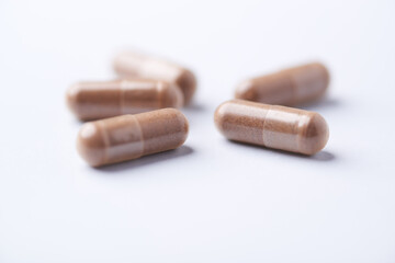 Ashwagandha (Withania somnifera) capsules. Concept for a healthy dietary supplementation. Bright paper background. Close up. Copy space.