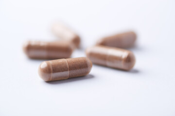 Ashwagandha (Withania somnifera) capsules. Concept for a healthy dietary supplementation. Bright paper background. Close up. Copy space.