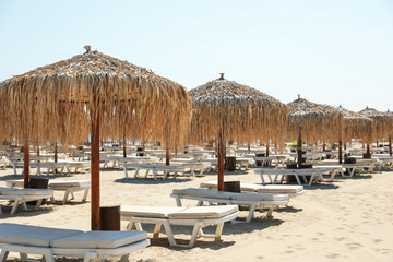 Beautiful straw umbrellas and sunbeds on sandy beach