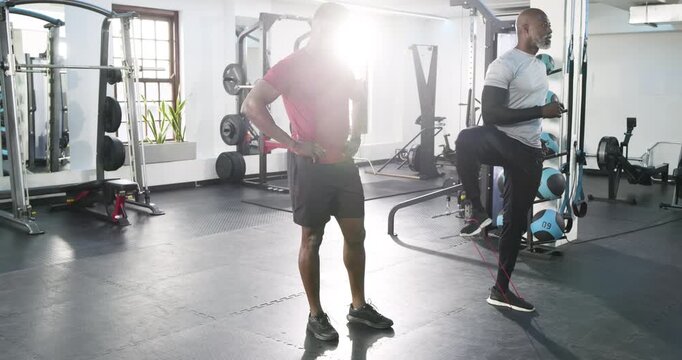 African American client following trainer demo, stepping into band raising knees in gym, copy space