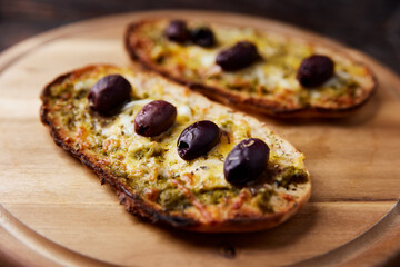 Bruschetta with mozzarella and cheddar cheese, olive pesto and kalamata olives. on wooden background. Soft focus. Close up	