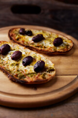 Bruschetta with mozzarella and cheddar cheese, olive pesto and kalamata olives. on wooden background. Soft focus. Close up	