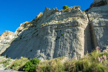 Layered Cliff with Vegetation Under Blue Sky