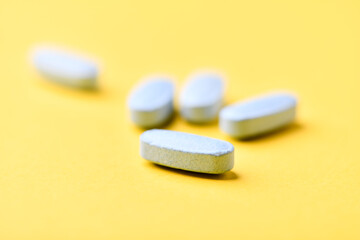 Multivitamin tablets on bright paper background. Close up. Copy space