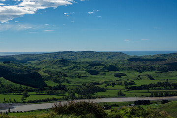 Lush Green Hills and River Under Blue Sky