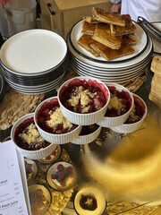 Assorted berry crumbles and layered pastries on display in a cafe