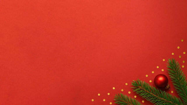 Holiday decoration featuring red background with gold confetti and green pine branches alongside a glossy red ornament - Powered by Adobe