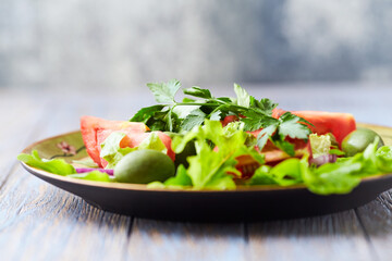 Healthy and tasty salad with tomatoes, olives, cucumber, and lettuce.
