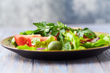 Healthy and tasty salad with tomatoes, olives, cucumber, and lettuce.