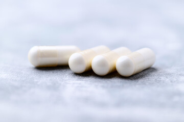 Creatine capsules on bright wooden background. Soft focus. Close up. Copy space.	