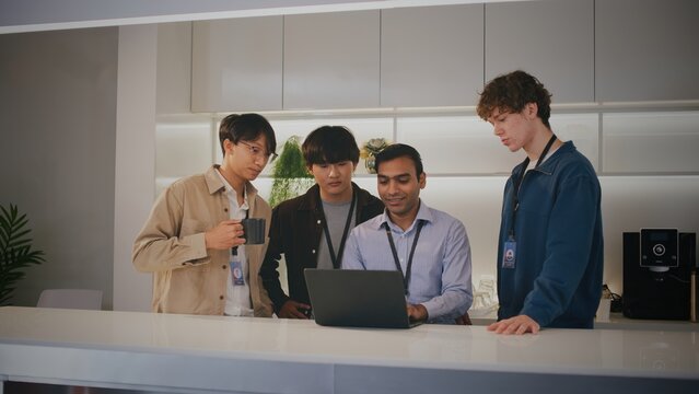 Diverse people in modern startup office. These focused highschool student interns show teamwork and concentration looking together at laptop project for company