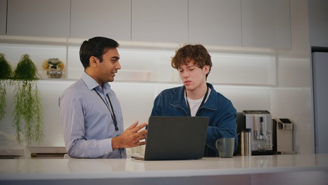 Diverse people collaborating in startup office. focused highschool student gets advice from mentor for project on laptop creating supportive environment