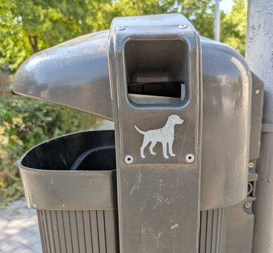 Dispensador de bolsas para excrementos de perro, en el lateral de una papelera en un parque p&uacute;blico 