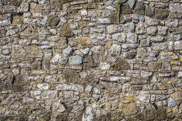 Irregular stone wall texture made of mixed rocks and mortar, suitable for backgrounds or architectural design.