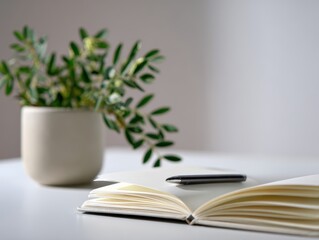 Naklejka premium Minimalist desk setup with an open notebook, pen, and a plant. Study space, organized. Clean, simple.