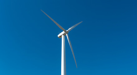Tall White Wind Turbine Against Blue Sky.