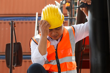 Asian worker have health and work problems while resting after work at shipping port, construction site or factory warehouse. Freight transport logistics or industrial plant.