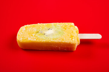 fresh mango and milk flavor popsicle with slice of kiwi fruit on red