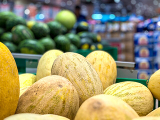 A bunch of yellow melons are piled up in a crate