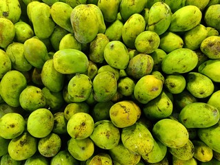 a pile of yellowish green mangoes from local farmers at a fruit shop