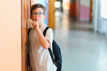 Schoolboy making silence gesture in school hallway