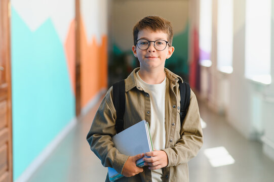 Smiling pupil holding school books in school hallway