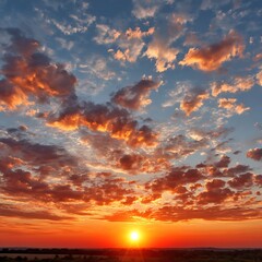 Naklejka premium Vibrant sunset with dramatic clouds painting the sky in fiery orange and blue hues