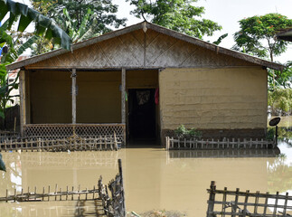A clay and bamboo made house partially submerged by floodwater in Assam