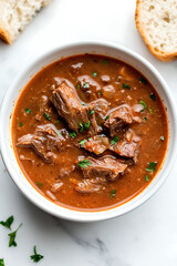 Hearty beef stew in a bowl, garnished with fresh herbs. A comforting and flavorful dish perfect for a cozy meal. Served with crusty bread.