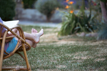 Woman relaxing, reading a book in the garden.