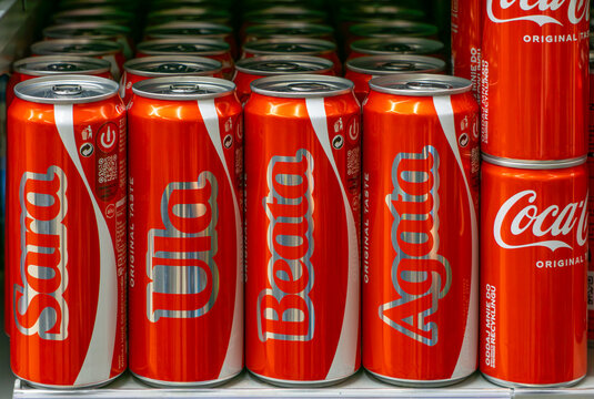 Coca-Cola cans with personalized names&mdash;Sara, Ula, Beata, Agata&mdash;displayed on a store shelf. 