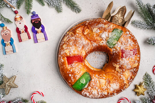 Roscon de reyes with cream and christmas ornaments on a white background, top view. Roscon is a traditional Spanish Christmas pastry cake with decoration. Kings day concept spanish three kings cake.