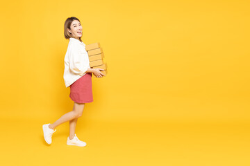 Happy Asian woman holding package parcel box isolated on yellow background, Delivery courier and shipping service concept