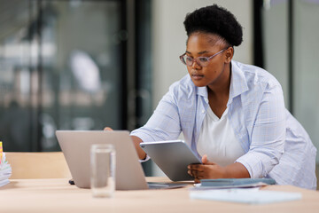 Obraz premium Young happy business African American woman working with tablet in corporate office Free Space,