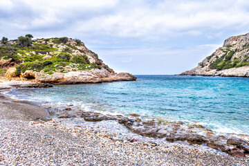 Iero beach on Ikaria island, Greece cove with Ikarian sea waves washing on coast shore rocks by Dionysos cave temple in summer