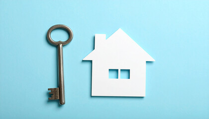 Old key and house silhouette cut out on pastel blue surface, hope for homecoming