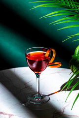 Elegant cocktail served in a stylish glass with an orange twist on a marbled table under soft lighting