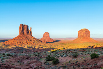 Monument Valley famous east west mittens and Merrick buttes at horizon colorful red sunset in Arizona, USA with orange canyon rock formations